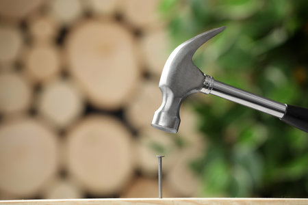 Hammering nail into wooden surface against blurred backgroundの写真素材