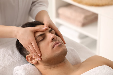 Man receiving facial massage in beauty salonの写真素材