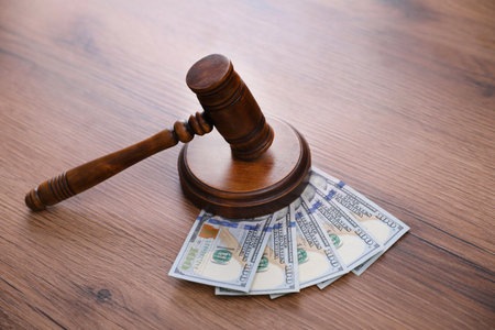 Judge's gavel and dollar bills on wooden tableの写真素材