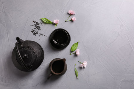 Beautiful traditional tea ceremony set and sakura flowers on light gray table, flat lay. Space for textの写真素材