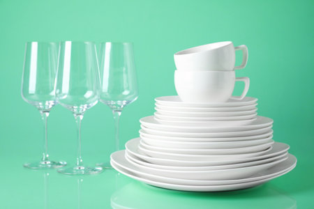Set of clean tableware on light green backgroundの写真素材