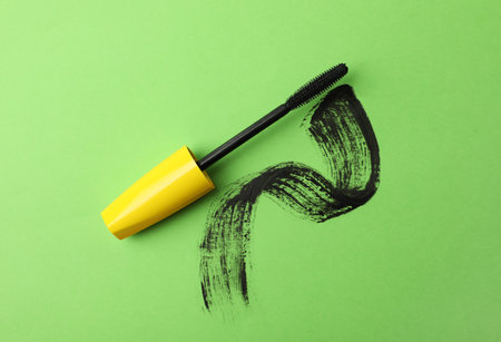 Mascara wand and smear on green background, top view. makeup productの写真素材