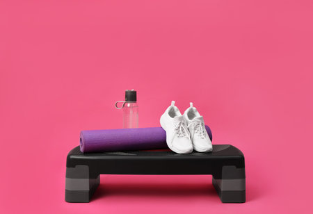 Step platform, mat, shoes and bottle of water on pink background. sports equipmentの写真素材