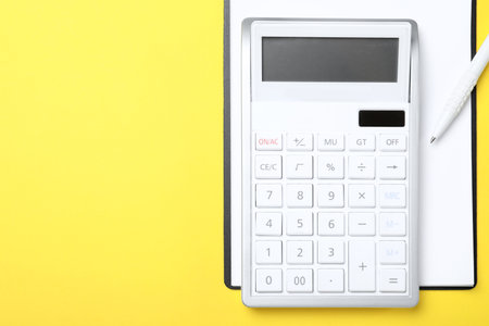Calculator, clipboard and pen on yellow background, top view. Space for textの写真素材