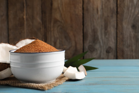Natural coconut sugar in bowl on light blue wooden table, space for textの写真素材