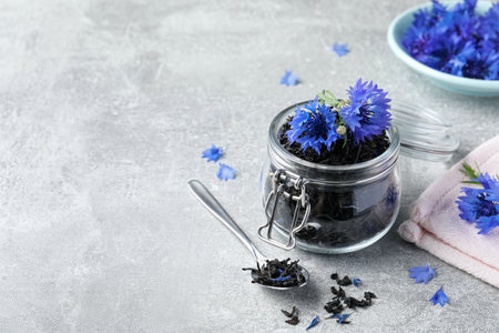 Dry tea leaves and cornflowers on light table. Space for textの写真素材