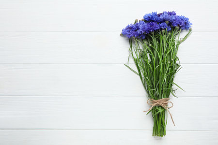 Bouquet of beautiful cornflowers on white wooden table, top view. Space for textの写真素材