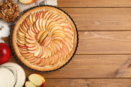 Delicious homemade apple tart and ingredients on wooden table, flat lay. Space for textの写真素材