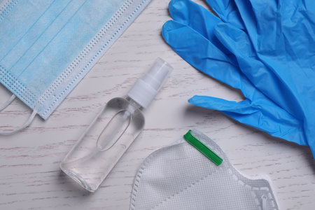 Protective masks, medical gloves and antiseptic on white wooden background, flat layの写真素材