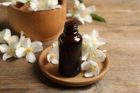 Jasmine essential oil and fresh flowers on wooden tableの写真素材