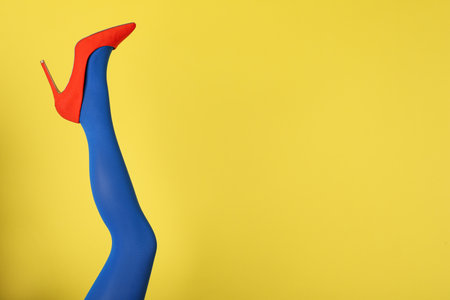 Woman wearing blue tights and high heel shoe on yellow background, closeup. Space for textの写真素材