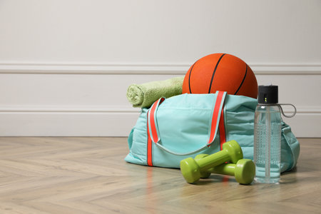 Blue gym bag with sports accessories on floor near white wall indoors, space for textの写真素材