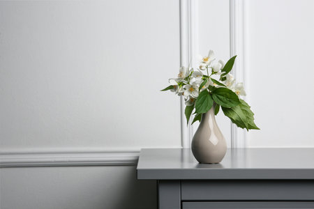 Beautiful bouquet with fresh jasmine flowers in vase on gray table indoors, space for textの写真素材