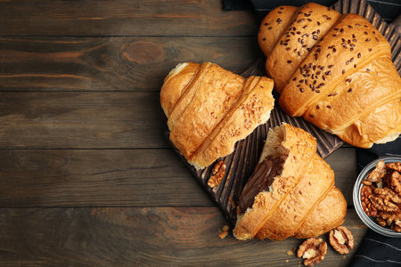 Flat lay composition with tasty croissants and walnuts on wooden table. Space for textの写真素材