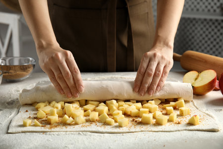 Woman making delicious apple strudel at table, closeupの写真素材