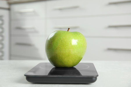 Green apple and modern digital scale on tableの写真素材