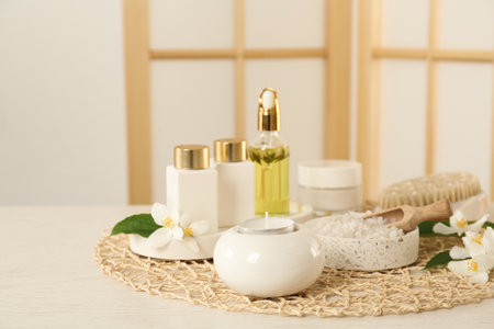Composition with beautiful jasmine flowers and skin care products on white wooden table indoorsの写真素材