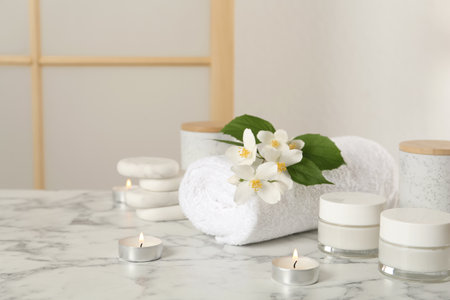 Composition with beautiful jasmine flowers and skin care products on white marble table indoors, space for textの写真素材