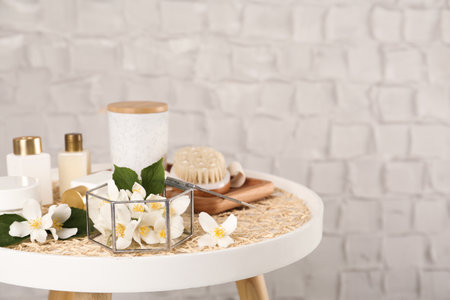 Composition with beautiful jasmine flowers and skin care products on white table, space for textの写真素材