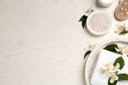 Flat lay composition with sea salt and beautiful jasmine flowers on white wooden table, space for textの写真素材
