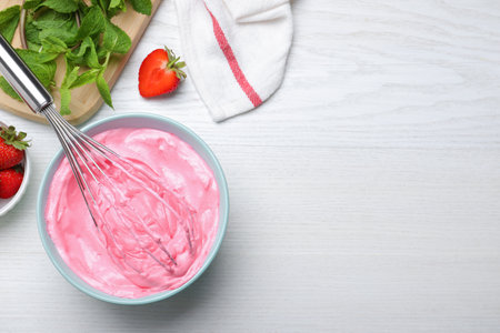 Strawberry cream with balloon whisk on white wooden table, flat lay. Space for textの写真素材
