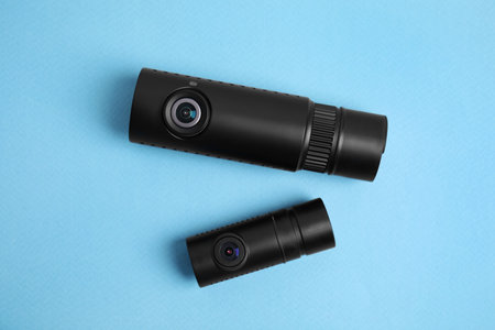 Black modern car cameras on turquoise background, flat lay