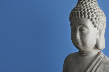 Beautiful stone Buddha sculpture on blue background. Space for textの写真素材