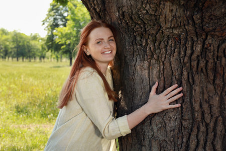 beautiful woman hugging tree trunk in forestの写真素材