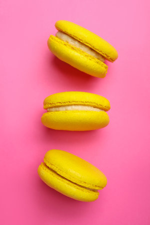Delicious yellow macarons on pink background, flat layの写真素材