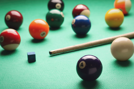 Many colorful billiard balls, cue and chalk on green tableの写真素材