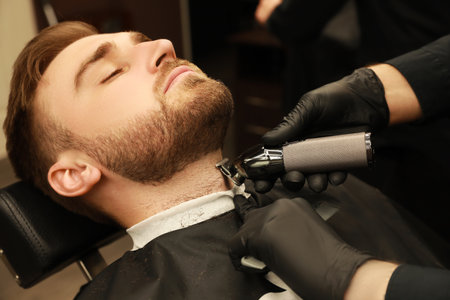 Professional hairdresser working with client in barbershopの写真素材