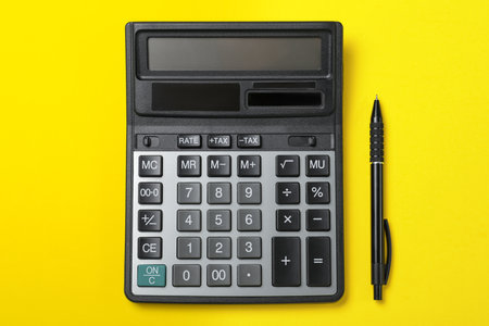 Calculator and pen on yellow background, flat layの写真素材