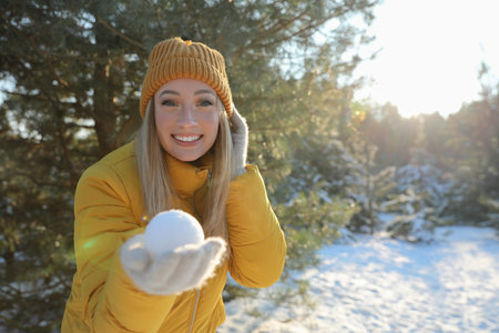 Woman holding snowball outdoors on winter day, space for textの写真素材