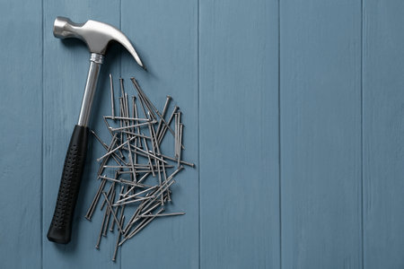 Hammer and metal nails on light blue wooden table, flat lay. Space for textの写真素材