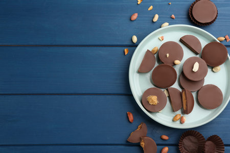 Flat lay composition with delicious peanut butter cups on blue wooden table, space for textの写真素材