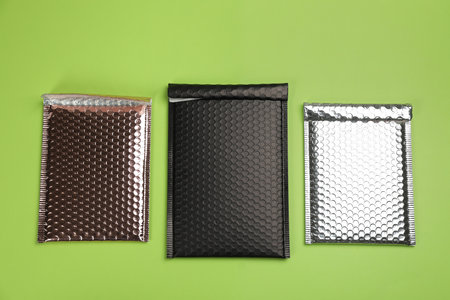 Three padded envelopes with polyethylene wrap on green background, flat layの写真素材