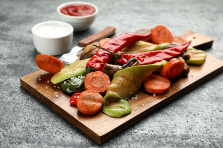 Wooden board with delicious grilled vegetables on gray table, closeupの写真素材