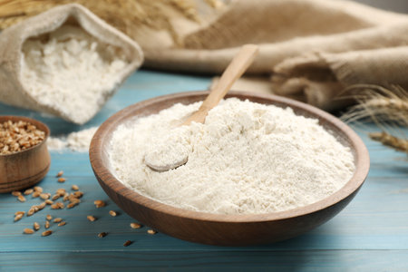 Wheat flour in bowl on light blue wooden tableの写真素材
