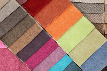 Fabric samples of different colors as background, top view