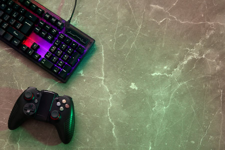 Modern RGB keyboard and game pad on gray table, flat lay. Space for textの写真素材