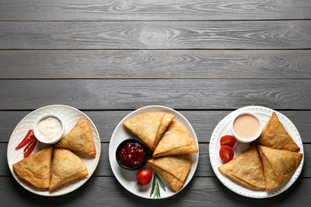 Fresh delicious crispy samosas served on gray wooden table, flat lay. Space for textの写真素材