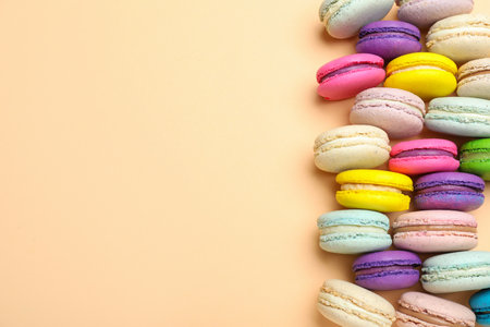 Delicious colorful macarons on beige background, flat lay. Space for textの写真素材