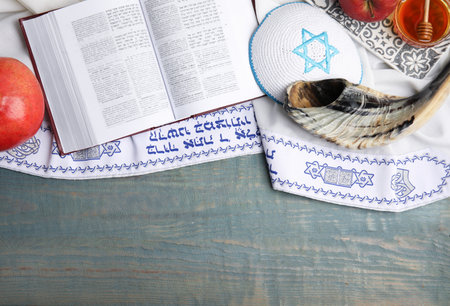 Flat lay composition of Rosh Hashanah holiday symbols on wooden table. Book Torah and tallit with...