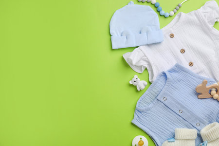 Flat lay composition with baby clothes and accessories on green background, space for textの写真素材