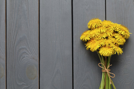 Beautiful dandelion bouquet on gray wooden table, top view. Space for textの写真素材