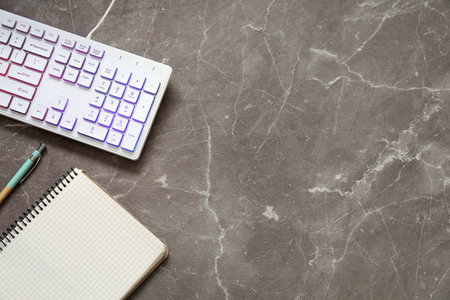 Modern RGB keyboard and stationery on gray table, flat lay. Space for textの写真素材