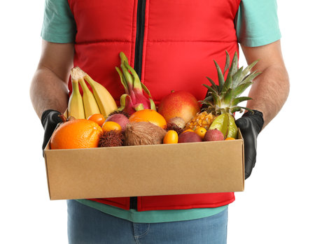 Courier holding box with assortment of exotic fruits on white background, closeupの写真素材