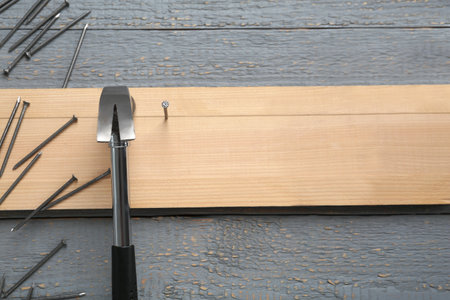 Hammering nails into plank on gray wooden table, flat lay. Space for textの写真素材