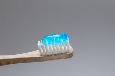 Wooden brush with toothpaste on gray background, closeupの写真素材