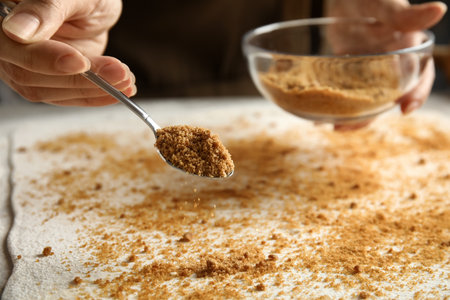 Woman pouring brown sugar onto dough while making pie at table, closeupの写真素材